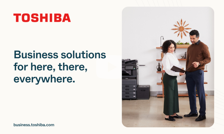 Two people stand by a printer in an office. The text reads, Business solutions for here, there, everywhere. The Toshiba logo is at the top left, and a website link is at the bottom left.