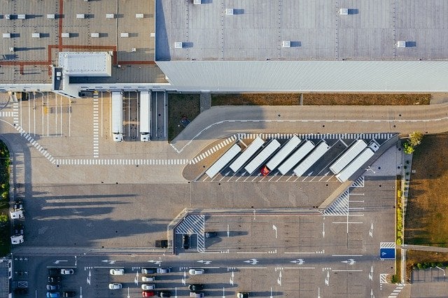 An aerial view of parking with multiple trucks carrying shipping containers.